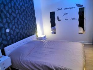 Un dormitorio con una cama y una pared con algunas fotos en Bel appartement t2 rdc tout équipé avec cour les cocons de Madenn, en Lamballe