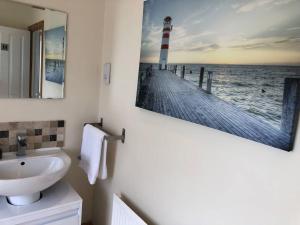 baño con lavabo y una foto de un faro en Edinburgh Street Home - Beautiful House with Free Parking and Wifi, Equipped with comfy furnitures en Swindon