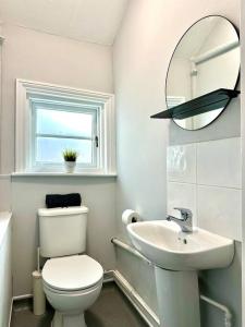 a white bathroom with a toilet and a sink at Massive 4 bedroom Duplex Apartment - Sleeps up to 10 People - Free Parking - 5 Minutes to the Best Beach! - Great Location - Fast WiFi - Smart TV - Newly decorated - sleeps up to 10! Close to Bournemouth & Poole Town Centre & Sandbanks in Bournemouth