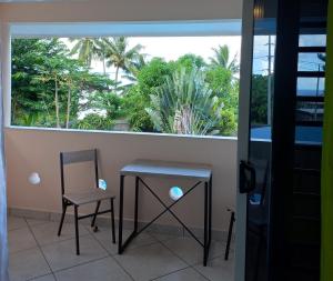 a balcony with a table and a chair and a window at Fare Tapu in Uturoa