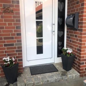 Una puerta blanca con dos plantas delante. en Ferienwohnung Halen Landkreis Cloppenburg, 