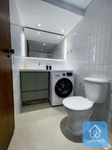 een badkamer met een toilet en een wasmachine bij Apartamento completo com píer e acesso ao mar 4 in Salvador