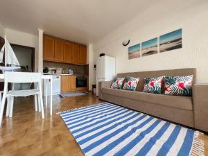a living room with a couch and a kitchen at Encantador apartamento com piscina in Costa da Caparica