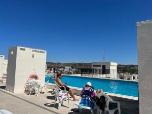 a group of people sitting around a swimming pool at Encantador apartamento com piscina in Costa da Caparica