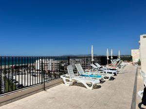 a row of chairs and tables on a balcony with the ocean at Encantador apartamento com piscina in Costa da Caparica
