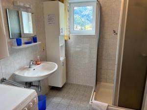 ein Bad mit einem Waschbecken und einer Dusche mit einem Fenster in der Unterkunft Haus Gletscherblick in Flattach