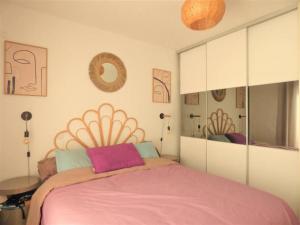 een slaapkamer met een groot bed en een roze deken bij L'Oasis, villa au calme, 400m plage à pied in Saint-Aygulf