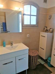 een badkamer met een wastafel, een spiegel en een koelkast bij L'Oasis, villa au calme, 400m plage à pied in Saint-Aygulf
