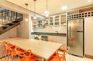 uma cozinha com uma mesa de madeira e cadeiras laranja em Lifespace Curitiba - Duplex Incrível, 2 Quartos, varanda, 2 garagens Batel em Curitiba