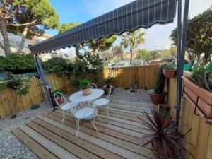patio ze stołem i krzesłami na drewnianym tarasie w obiekcie LA REPOSADE w mieście Sanary-sur-Mer