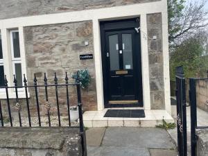a black door on a stone house with a fence at Castle View Accommodation in Inverness