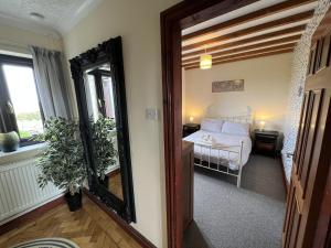 a bedroom with a mirror and a bed in a room at 4 Bed Farmhouse - Pets - Garden - Parking in Beaumaris