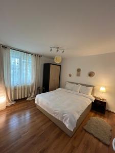 a bedroom with a large white bed and wooden floors at Scandinavia Apartament in Piatra Neamţ +9 photos