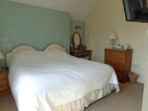 a bedroom with a white bed and a dresser and a mirror at Staylittle Farm in Dolgellau