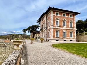 a large brick building with a stone walkway in front at Villa Pasqui 1914 e Limonaia in Città di Castello +28 photos