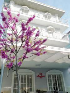 uma árvore com flores roxas em frente a um edifício em B&B Villa Madana em Rimini