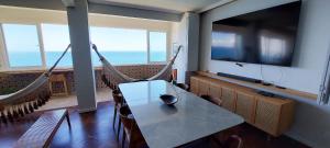 a room with a table and hammocks and a television at COBAR0108 - Edifício Oceania in Salvador