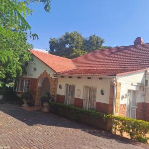 una casa con techo rojo y entrada de ladrillo en Moonlight Guesthouse en Pretoria