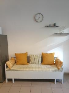 um sofá com almofadas laranja e um relógio na parede em CAMELLIA STUDIO apartment & parking em Riga