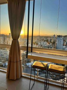 a room with a table and two chairs in front of a window at Hub Home - Vista Incrível in Criciúma