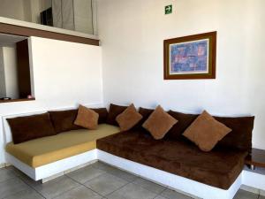 um sofá castanho com almofadas na parede em Suite Misión Juriquilla #5 em Juriquilla