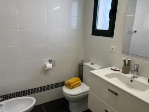 a bathroom with a white toilet and a sink at Tender Suite in Corralejo