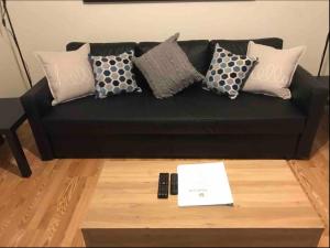 a black couch with pillows and a remote control at Walk 2mins to West Point Academy! Private 2br on Main in HEART of Highland Falls in Highland Falls