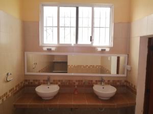 La salle de bains est pourvue de 2 lavabos et d'une fenêtre. dans l'établissement Guest house La Casa del Quetzal, à Mérida