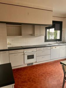cocina con electrodomésticos blancos y suelo rojo en Maison du parc, en Vernet