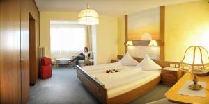 een hotelkamer met een bed en een vrouw in een stoel bij Alpenbad in Ramsau am Dachstein