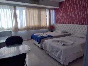 a hotel room with two beds and a table and chairs at Feira Palace Hotel in Feira de Santana
