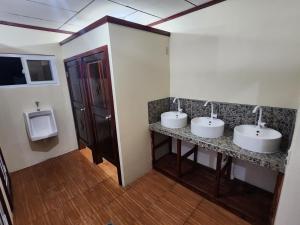 a bathroom with two sinks and a urinal and two mirrors at Fenix Hotel & Hostel in Utila