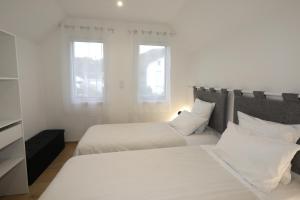 a white bedroom with two beds and two windows at Gîte les iris Fleurs des Pyrénées in Argelès-Gazost