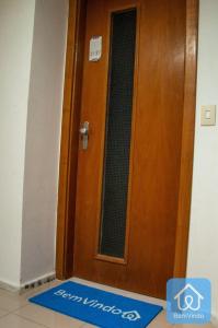 a wooden door with a blue welcome mat in front of it at Apartamento completo ao lado do Salvador Shopping in Salvador