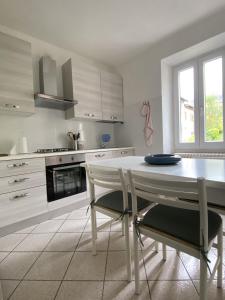 a white kitchen with a table and chairs in it at Casa Dilma in Lenno