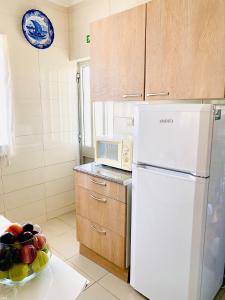 uma cozinha com um frigorífico branco e uma taça de fruta em Casa da Jesus - Lugar encantador com piscinaa em Provesende
