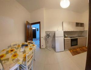 a kitchen with a table and a white refrigerator at Villa Vistasalentina Piano terra in Torre Colimena