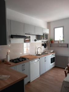 a kitchen with white cabinets and a sink and a stove at La Montagne Sud in Allemans