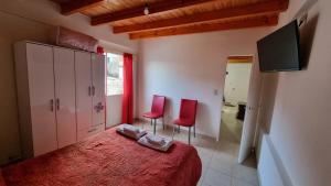 1 dormitorio con 1 cama roja y 2 sillas rojas en DEPARTAMENTO Matrimonial Glaciar Martial en Ushuaia