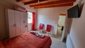 1 dormitorio con 2 sillas rojas y 1 cama en DEPARTAMENTO Matrimonial Glaciar Martial en Ushuaia