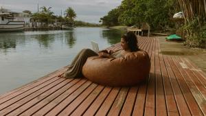 una mujer sentada en una silla de bolsa de frijoles con un portátil en Nômades Adventure Hostel & Coworking en Florianópolis