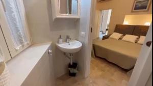 - une salle de bains blanche pourvue d'un lavabo et d'un lit dans l'établissement Casa Daniela, à Castagneto Carducci