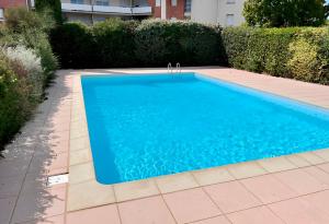 a swimming pool with blue water in a yard at RedLounge - Appartement avec Piscine et Jardin in Toulouse