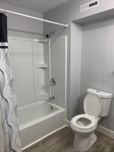 a white bathroom with a toilet and a bath tub at Entire Condo Minutes from Niagara Falls (USA) in Niagara Falls