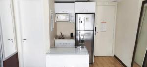 a kitchen with a stainless steel refrigerator and white cabinets at Flat em Moema na avenida Ibirapuera com cozinha, estacionamento, piscina e serviços in São Paulo