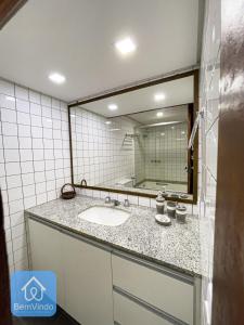 a bathroom with a sink and a large mirror at Apartamento aconchegante com píer e acesso ao Mar in Salvador