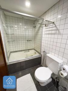 a bathroom with a toilet and a bath tub at Apartamento aconchegante com píer e acesso ao Mar in Salvador