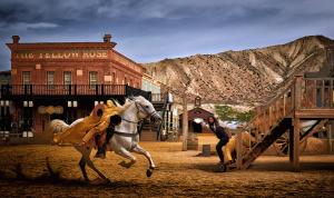 Un uomo che cavalca un cavallo bianco davanti a un palazzo di Alojamiento las Dunas alto a Tabernas