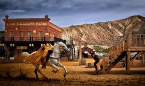 un hombre montando un caballo blanco delante de un edificio en Alojamiento las Dunas alto, en Tabernas
