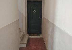 a black door in a hallway with a red brick floor at Casa Artisti in Carrara